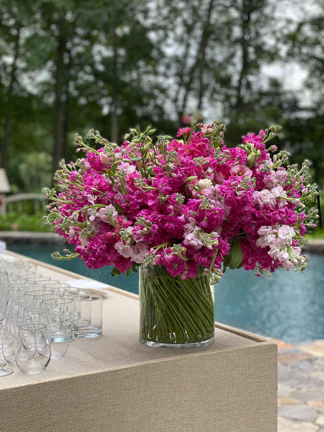 Bright pink floral arrangement on a pool-side bar, designed by Bedford Village Flower Shoppe
